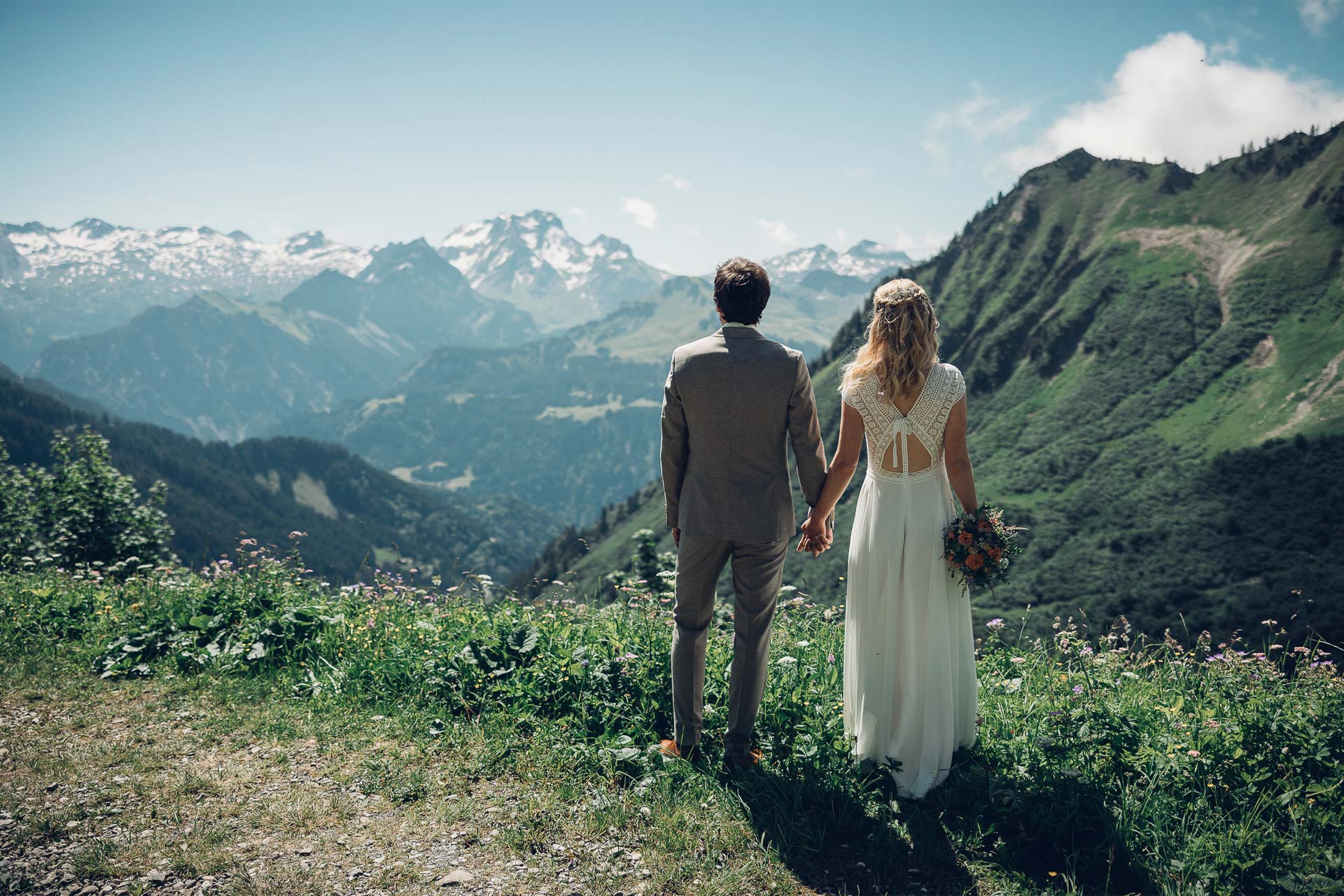 Brautpaar Hand in Hand mit Blick auf die Vorarlberger Alpen